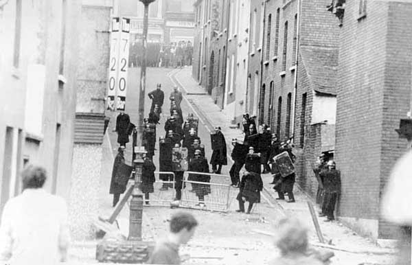 As the fighting moves back towards the Bogside local youths hold off the police in Harvey Street